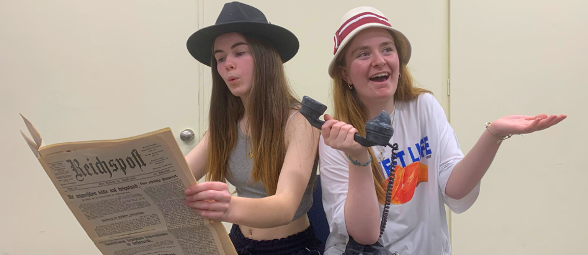 Bea and Isobel from the Youth Ensemble, rehearsing a scene from Emil whilst holding a German newspaper and an old telephone.