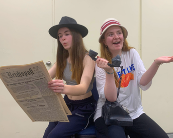 Bea and Isobel from the Youth Ensemble, rehearsing a scene from Emil whilst holding a German newspaper and an old telephone.
