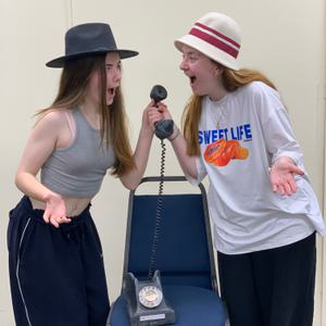 Youth Ensemble members Bea and Isobel rehearsing a scene with an old telephone.