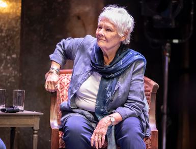 Judi Dench sitting in a red chair on stage