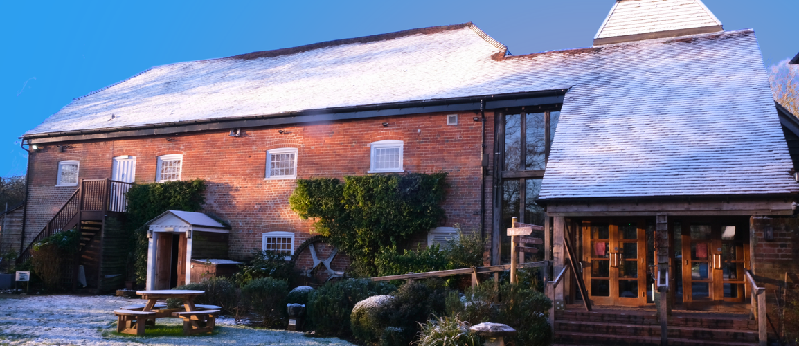 Watermill Theatre, covered in snow, with bright morning light shining on the orange brick.