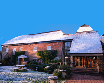 Watermill Theatre, covered in snow, with bright morning light shining on the orange brick.