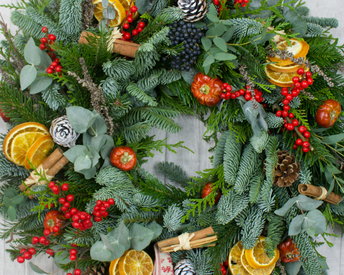 a wreath, made of pine branches and adorned with dried lemon, cranberries and white pinecones.
