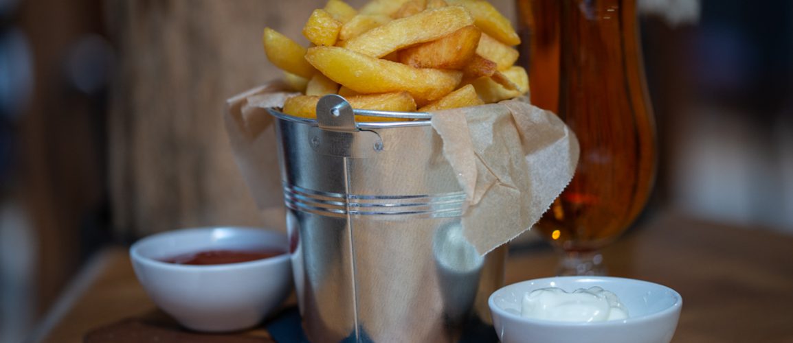 A bucket of chips with pots of ketchup and mayonnaise