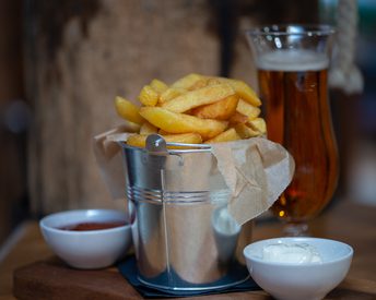 A bucket of chips with pots of ketchup and mayonnaise