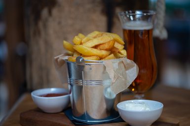 A bucket of chips with pots of ketchup and mayonnaise
