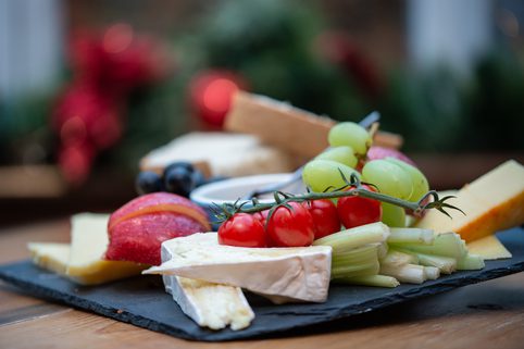 A selection of cheeses, tomatoes and fruit on a slate platter