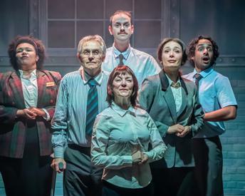 A team of 6 front of house staff, dressed in dress shirts and blazers, look toward the audience in a hopeful way.